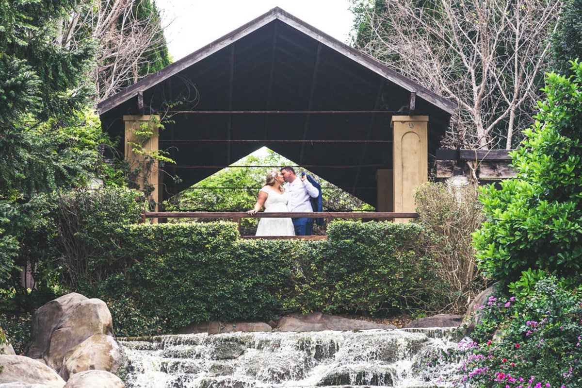 A couple kissing on the wooden bridge over the waterfall in the Oriental Garden at Hunter Valley Gardens