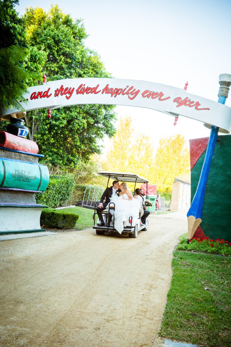 A couple kissing in a golf cart as they pass through the Storybook Garden storybook arch at Hunter Valley Gardens