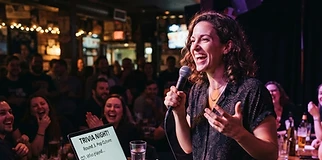 A certified Epic Trivia host running a game with a microphone in a bar