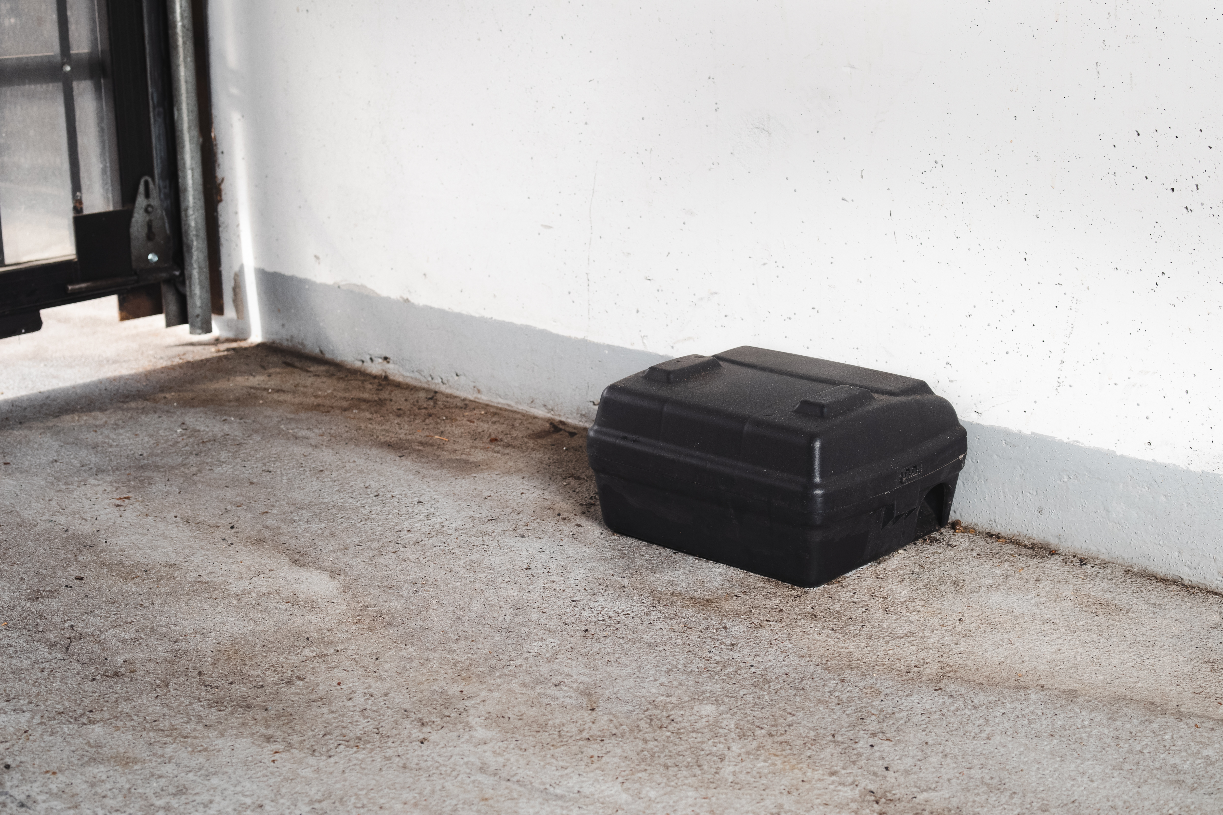 Tamper-resistant rodent bait station placed against wall