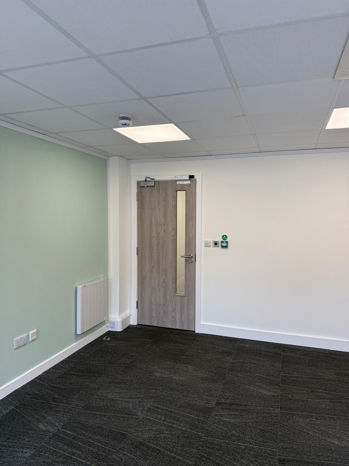 Sage green wall with wall-mounted heater and emergency door release