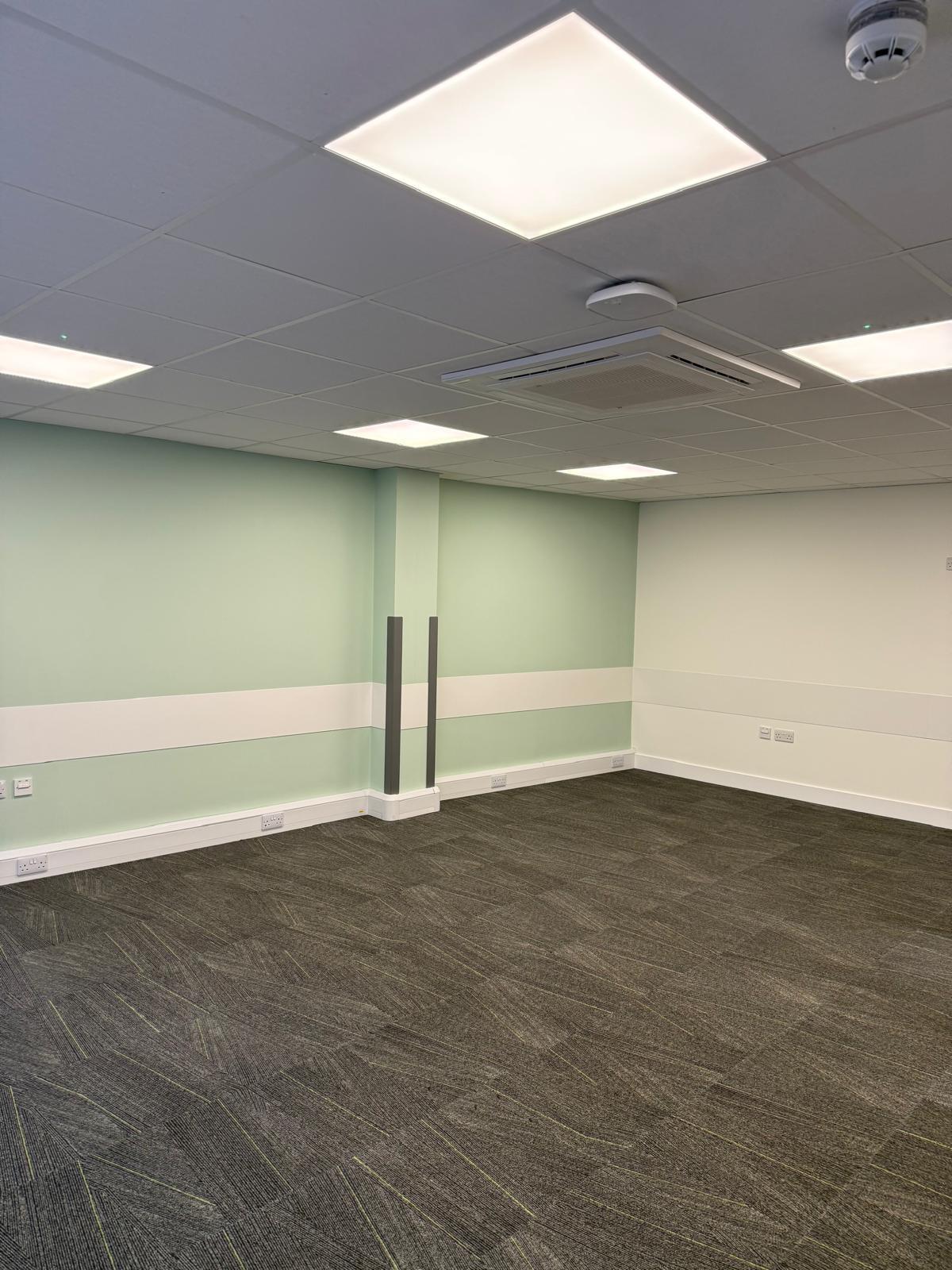 Empty office room with mint green accent wall and structural column