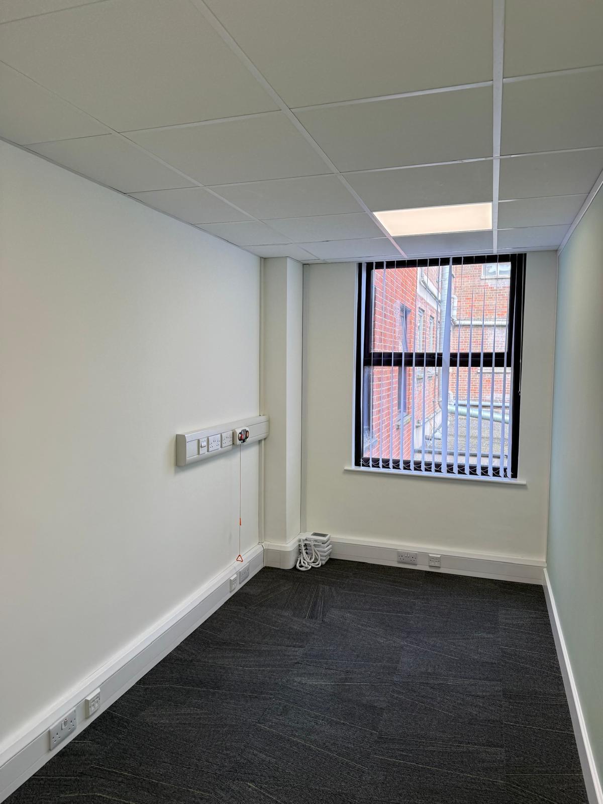 Small vacant office room with window and vertical blinds