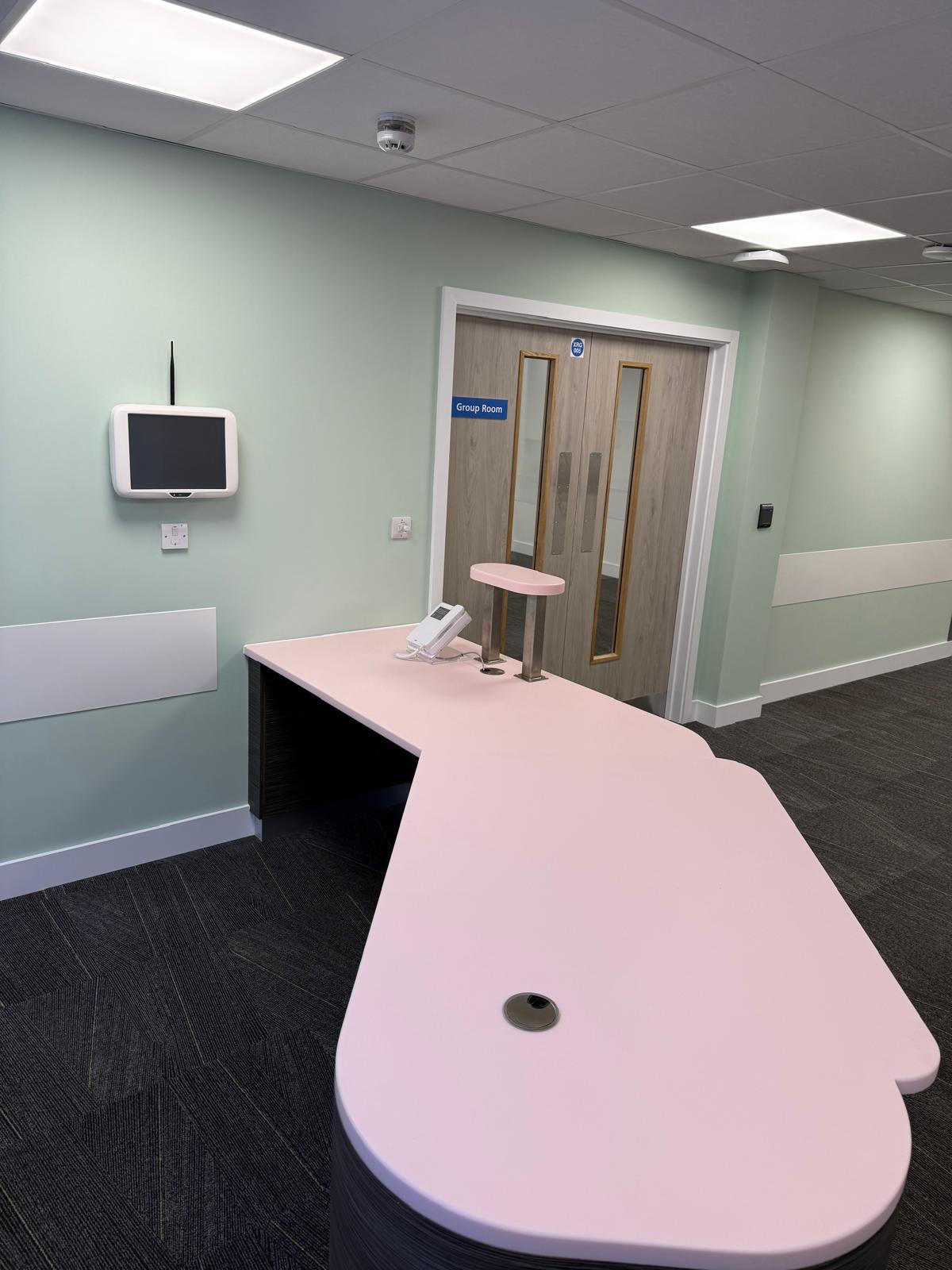 Reception desk with curved pink countertop and Group Room entrance
