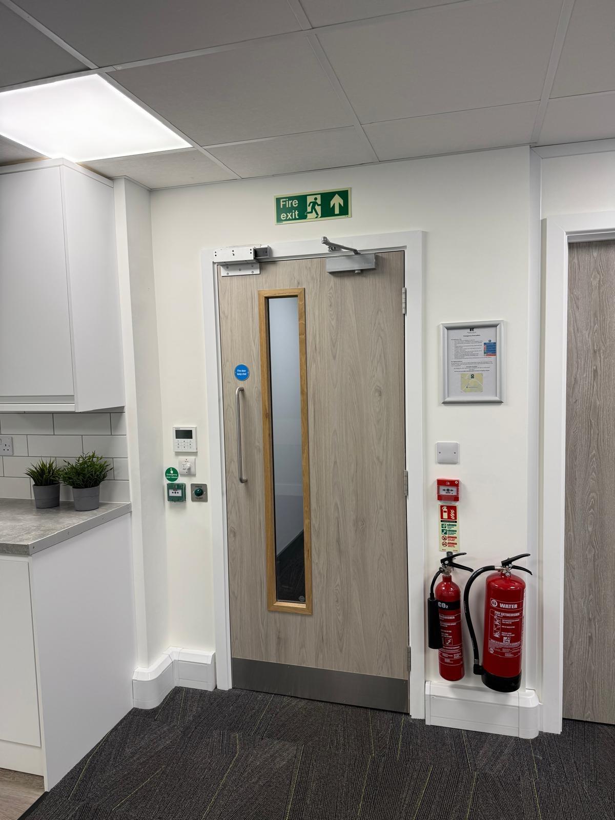 Fire exit door with extinguishers and evacuation signage