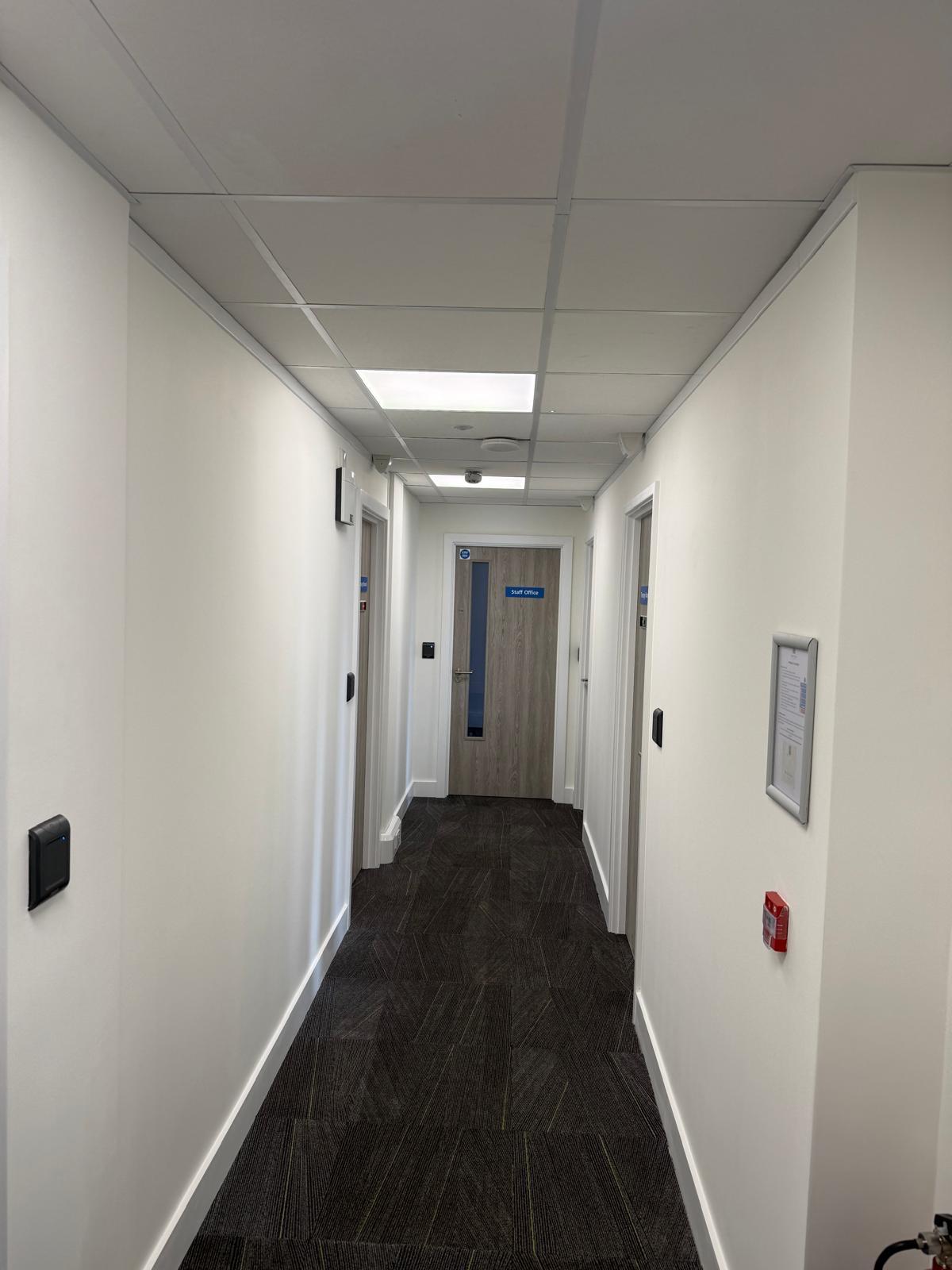 Narrow hallway with card reader, fire alarm call point and Staff Office door