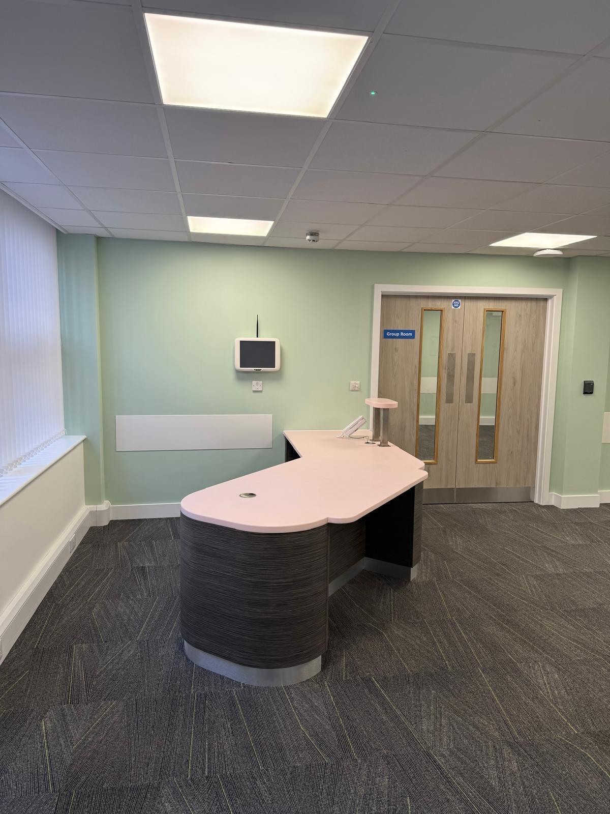 Reception desk with blush countertop and Group Room entrance