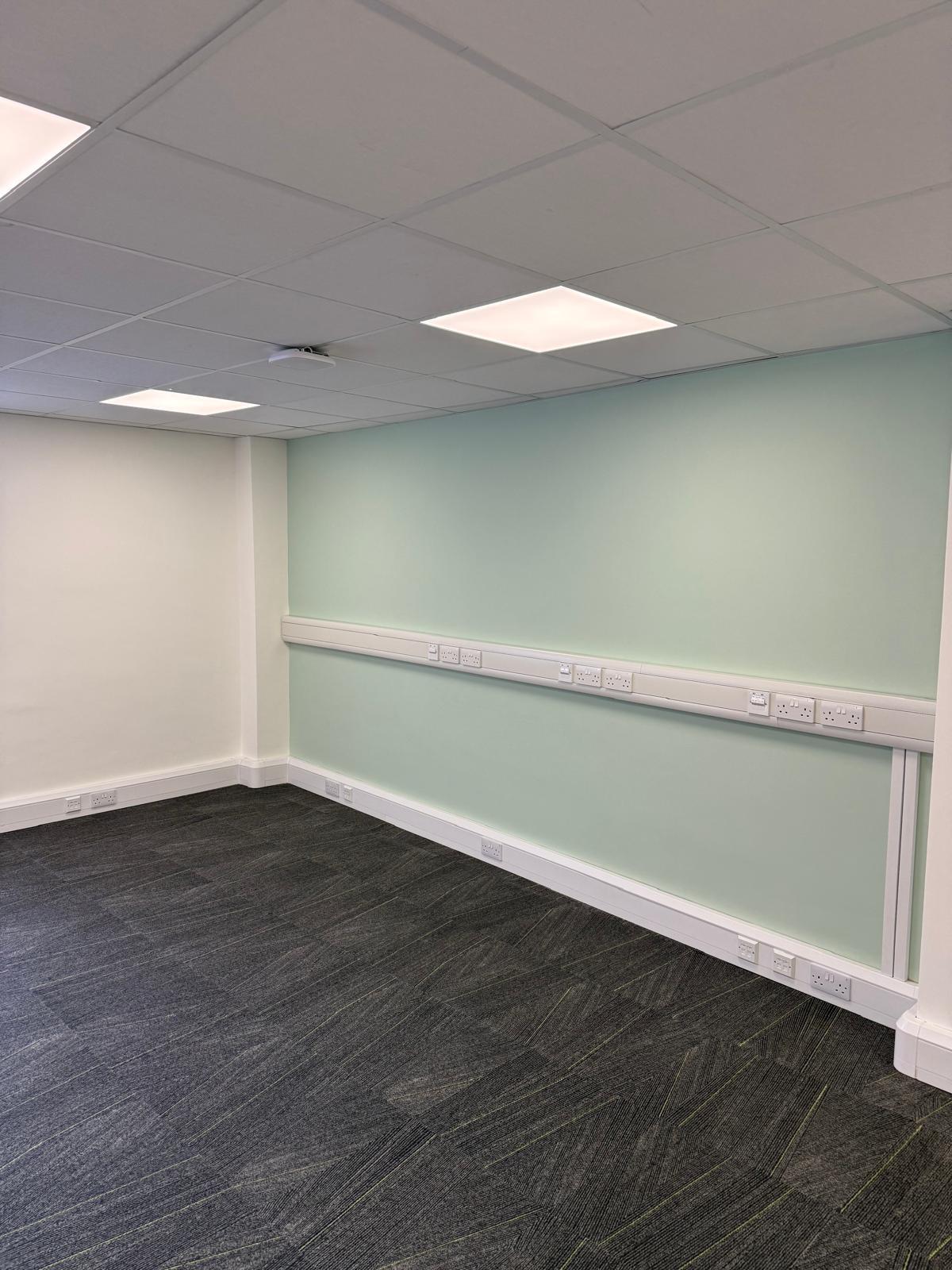 Office corner with mint green accent wall and power trunking