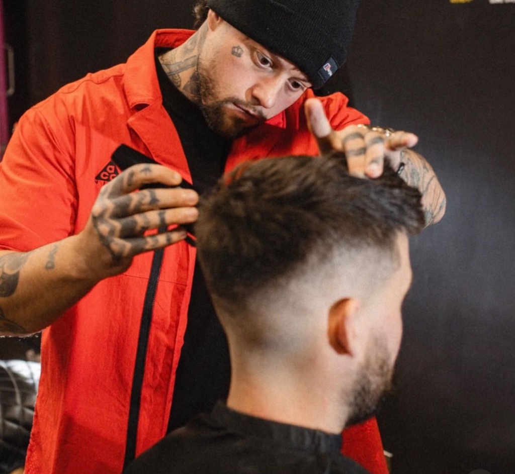 Barber in red shirt giving a fade haircut to client