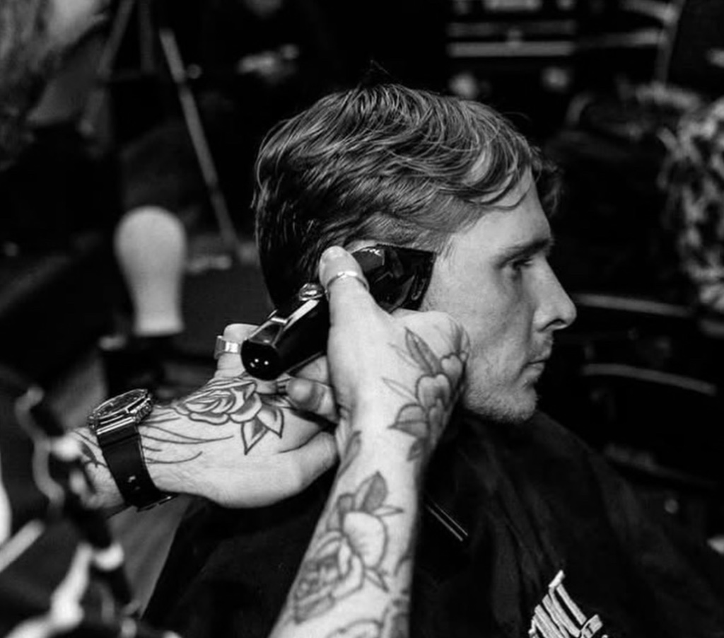 Black and white close-up of clipper work with tattooed barber hands