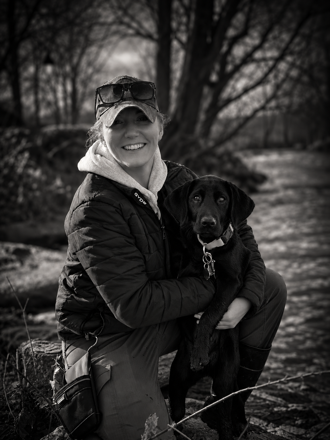 Trainer with her black Labrador puppy on the trail