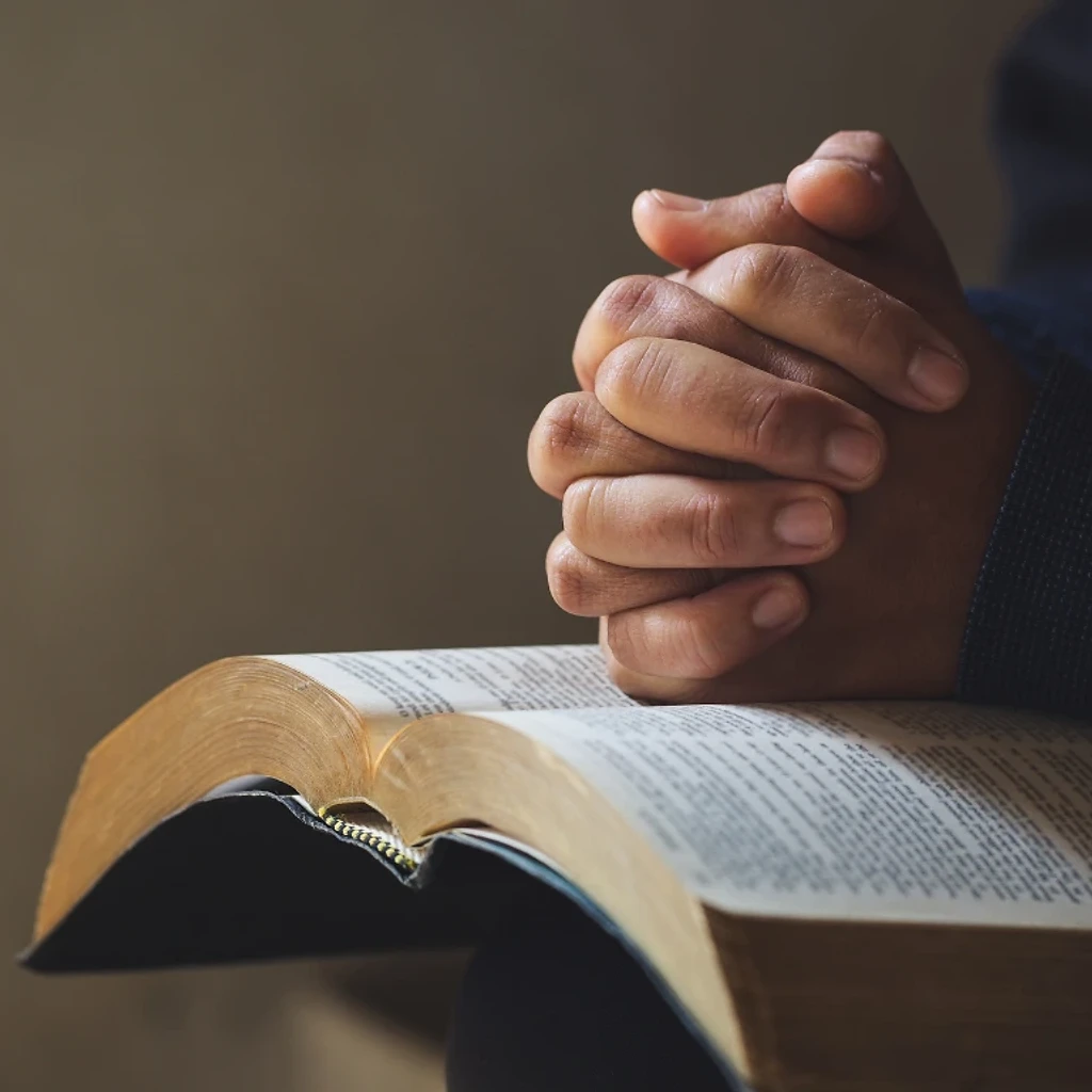 Hands journaling Scripture in a notebook beside an open Bible