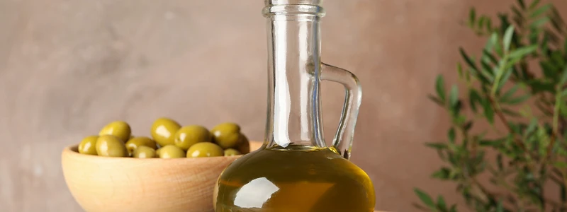 Golden olive oil in a glass carafe with fresh green olives