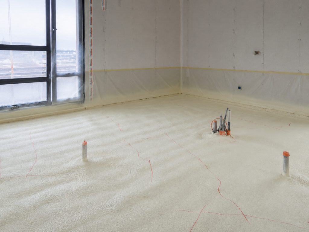 Isolation d'un plancher résidentiel en mousse polyuréthane projetée sur la surface du sol