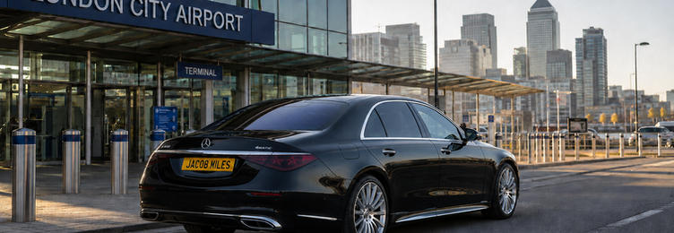 Black Mercedes-Benz S-Class chauffeur vehicle at London City Airport terminal with Canary Wharf skyline