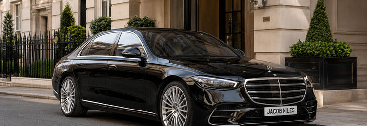 Black Mercedes-Benz S-Class chauffeur vehicle parked outside an elegant stone building entrance in London