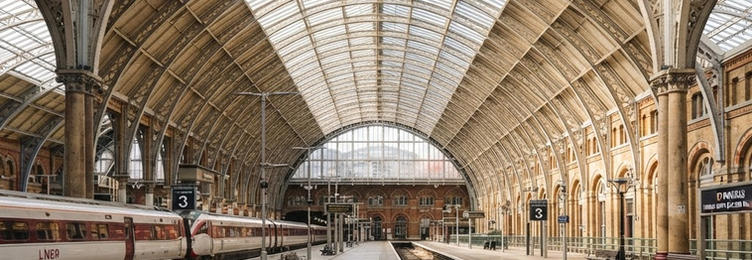 Grand London railway station interior with Victorian iron and glass architecture in bright natural light