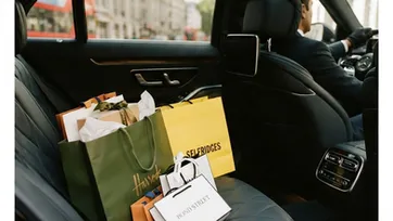 Luxury shopping bags arranged on the back seat of a chauffeur-driven Mercedes for a London shopping day