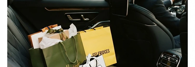 Luxury shopping bags arranged on the back seat of a chauffeur-driven Mercedes for a London shopping day