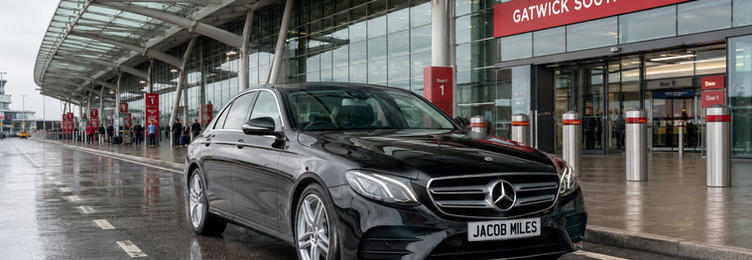 Black Mercedes-Benz E-Class chauffeur vehicle at Gatwick South Terminal drop-off