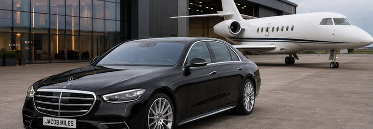 Jacob Miles Mercedes S-Class chauffeur vehicle parked on the tarmac in front of a private aviation hangar