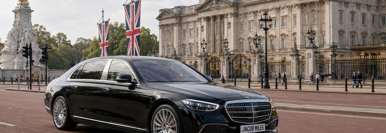 Black Mercedes-Benz S-Class chauffeur vehicle driving past Buckingham Palace and the Victoria Memorial in London