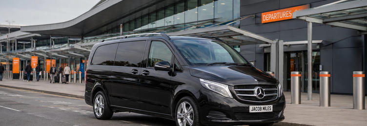 Black Mercedes V-Class chauffeur vehicle at London Luton Airport departures drop-off
