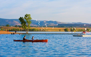 Paddlers in an orange kayak on Boulder Reservoir with mountains in the distance