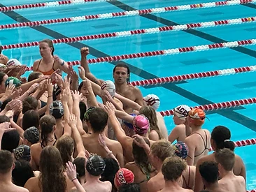 Swim team huddled together celebrating in the pool