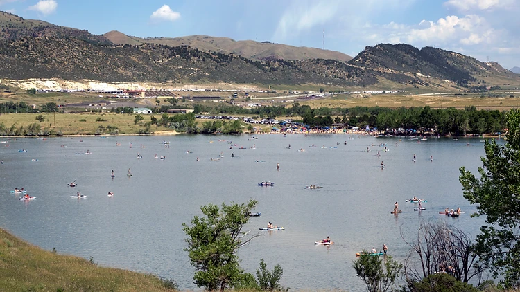 Paddleboarders and kayakers on a natural lake with foothills rising beyond