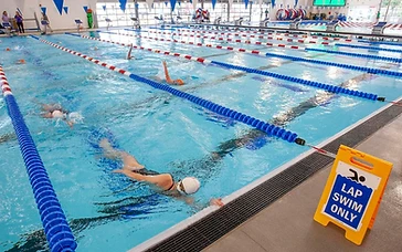 Swimmers doing laps in a bright indoor multi-lane pool