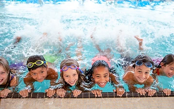 Children smiling at the pool edge during a swim lesson