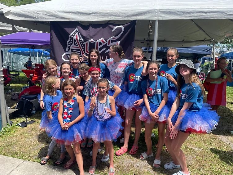 A team of young swimmers in matching tutus gathered together smiling