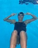 A swimmer smiling underwater making a peace sign