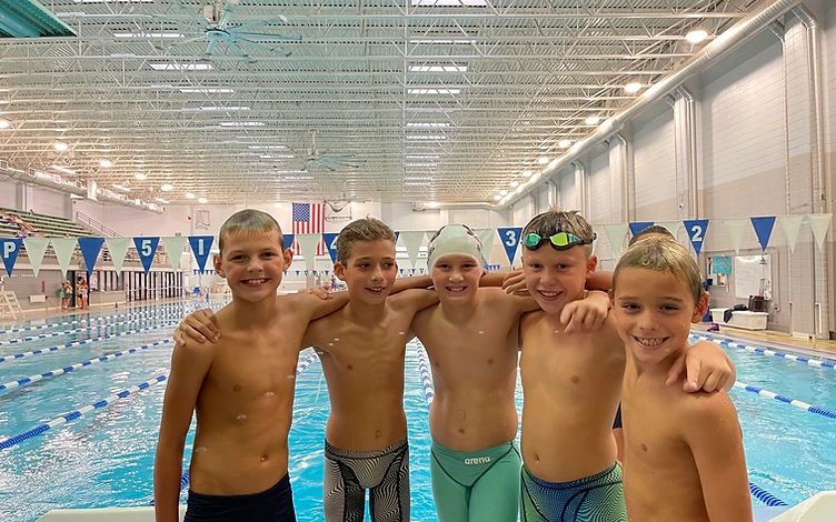 Young swimmers together at the pool deck, arms around each other after practice
