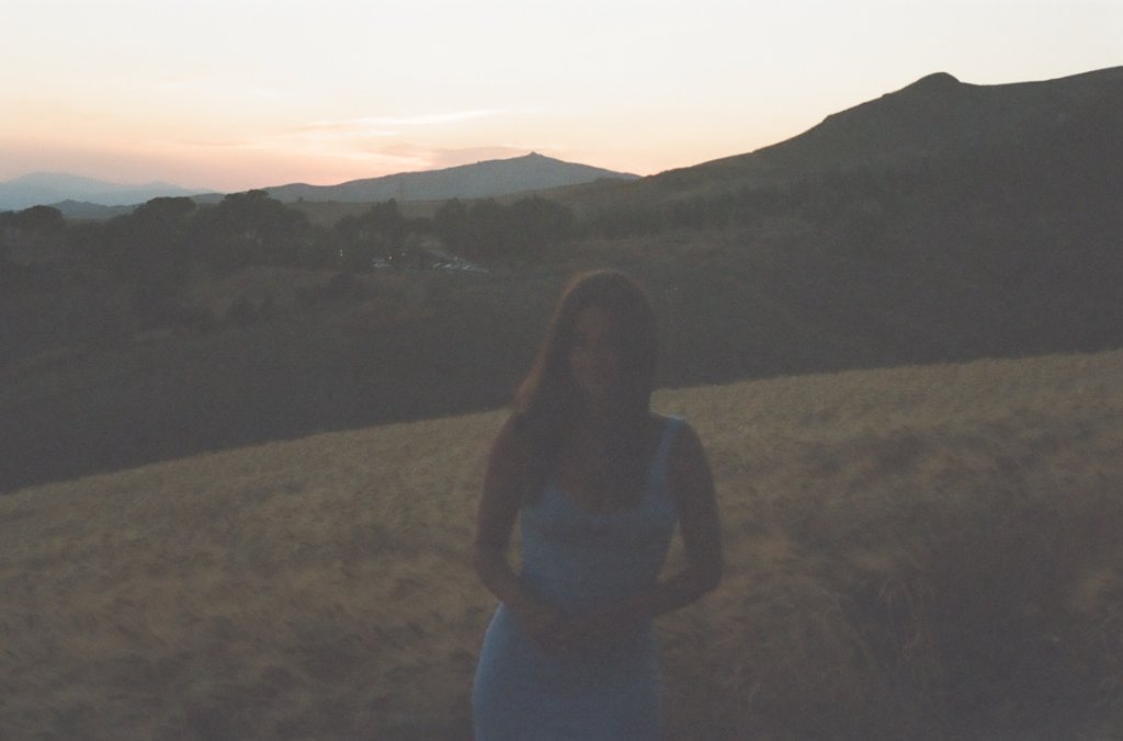 Andrea standing in a golden wheat field at sunset in Sicily