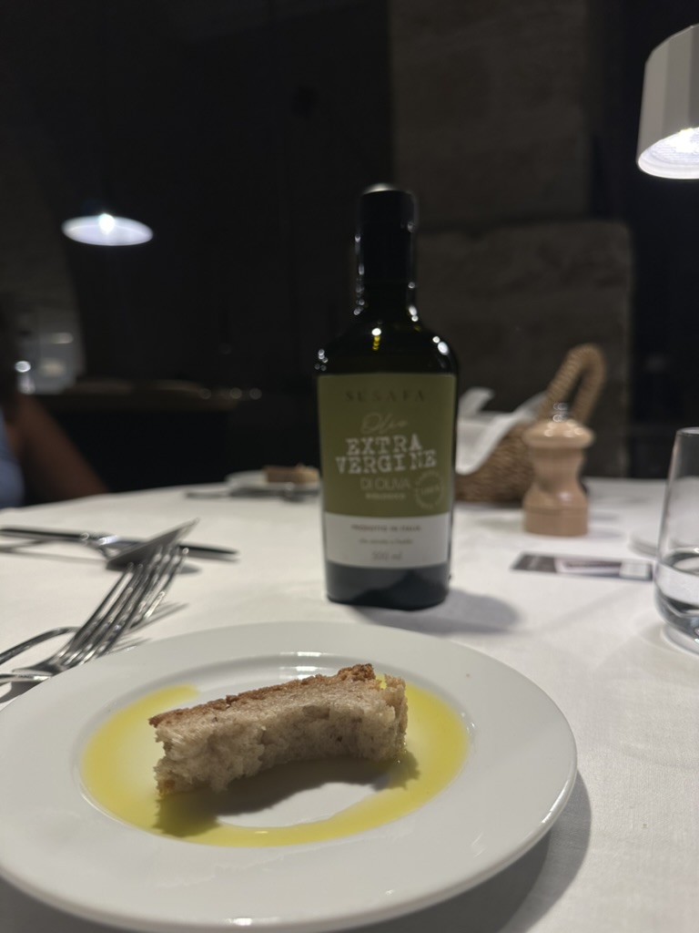 Rustic bread dipped in extra virgin olive oil beside a bottle on a restaurant table
