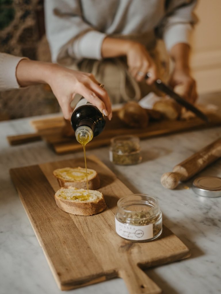 Pouring Susafa extra virgin olive oil over fresh bread