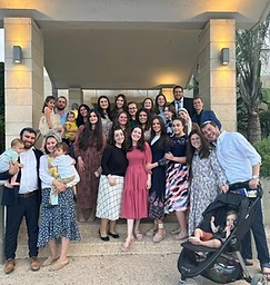 Young adults posing together under a stone archway on campus