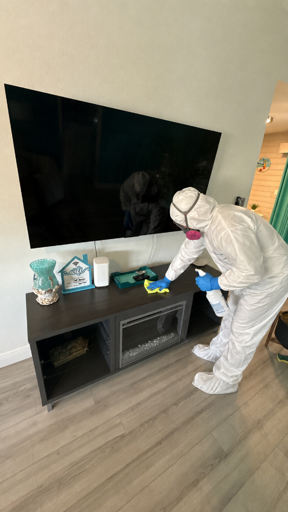 Certified technician in hazmat suit cleaning and sanitizing surfaces during mold remediation
