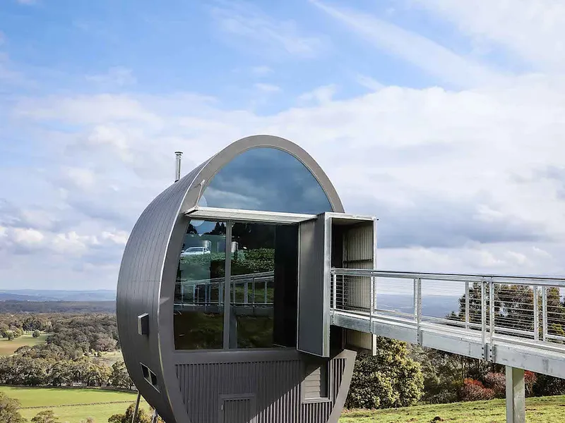 Modern circular architectural metal dwelling on a rural hillside