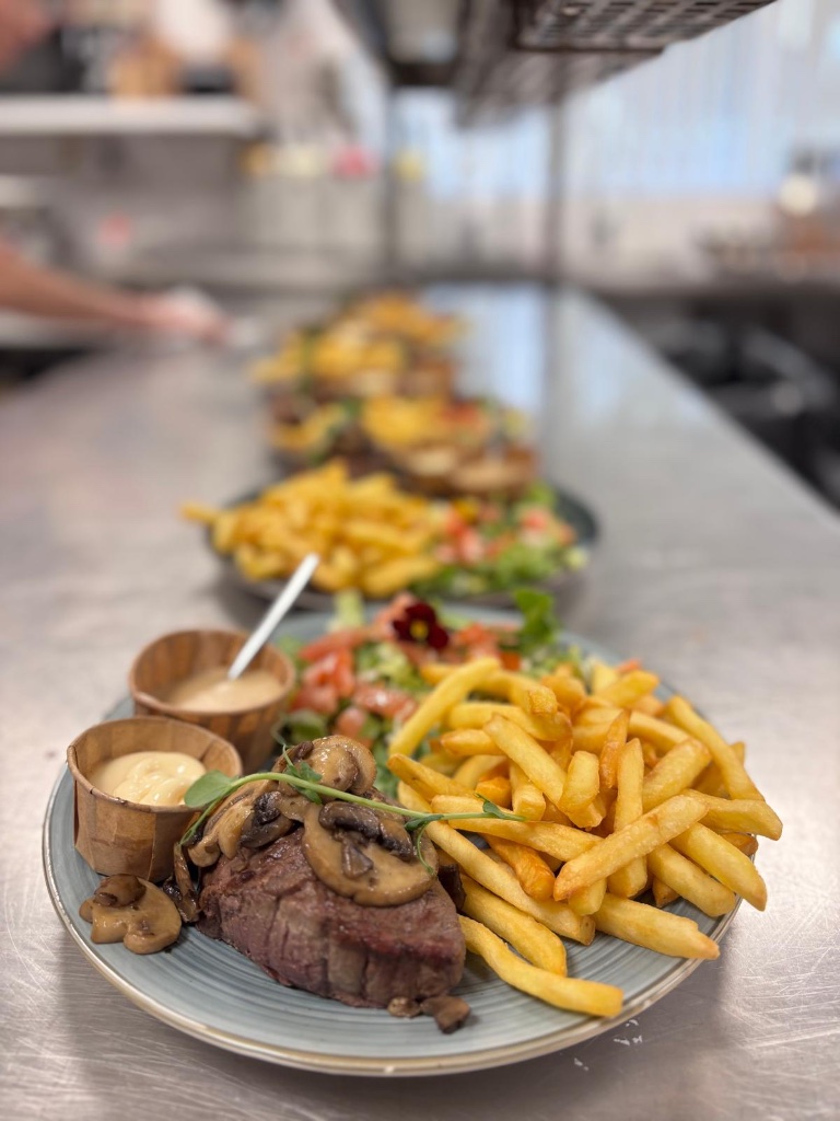 Borden met vlees, friet en salade in de keuken van De Meiboom