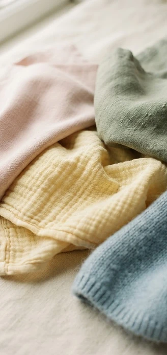 Folded pastel cotton and linen fabrics in blush, sage, and powder blue