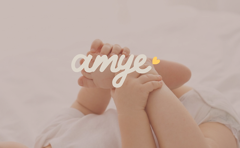 Infant's feet held gently, with the amye wordmark