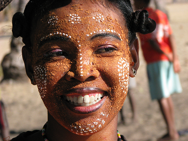 Smiling Malagasy woman wearing traditional masonjoany face paint