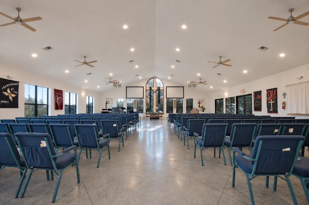 Bright sanctuary interior with warm wood ceiling fans and recessed lighting