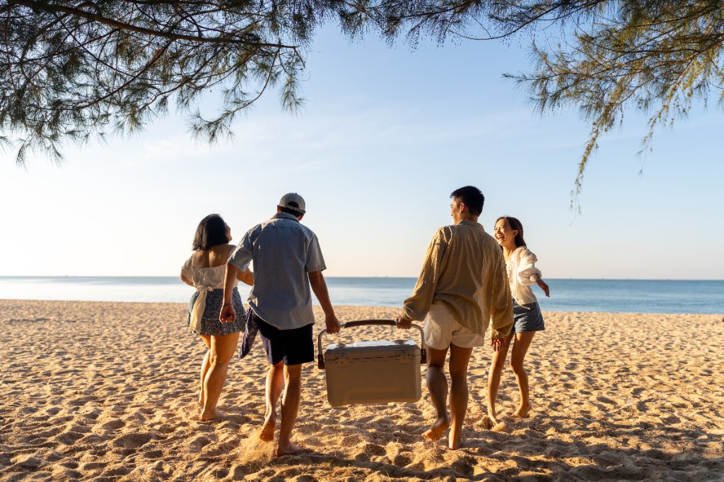 Friends carrying a cooler to the beach