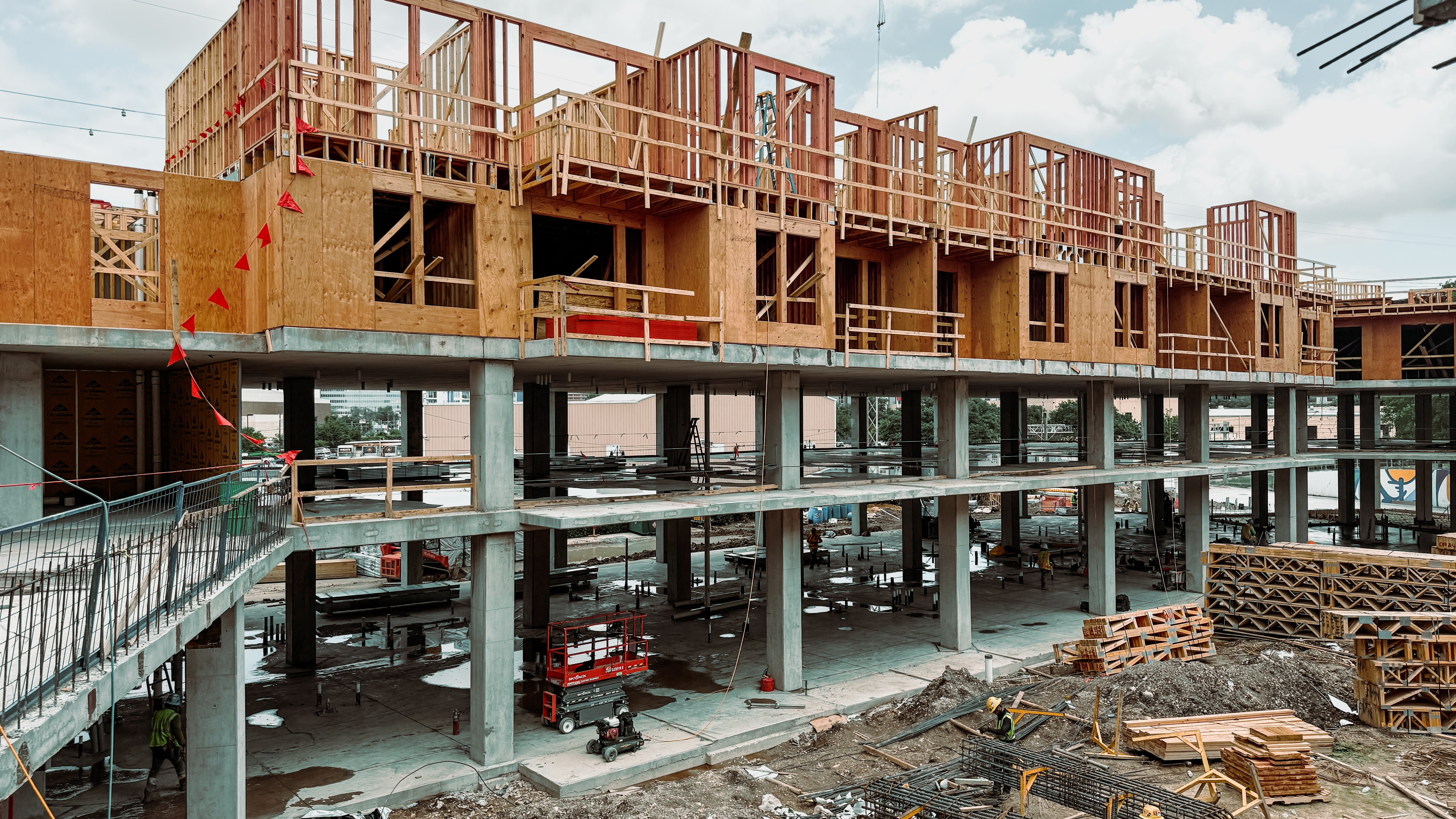 A multi-story building under construction with exposed wood framing and concrete structure