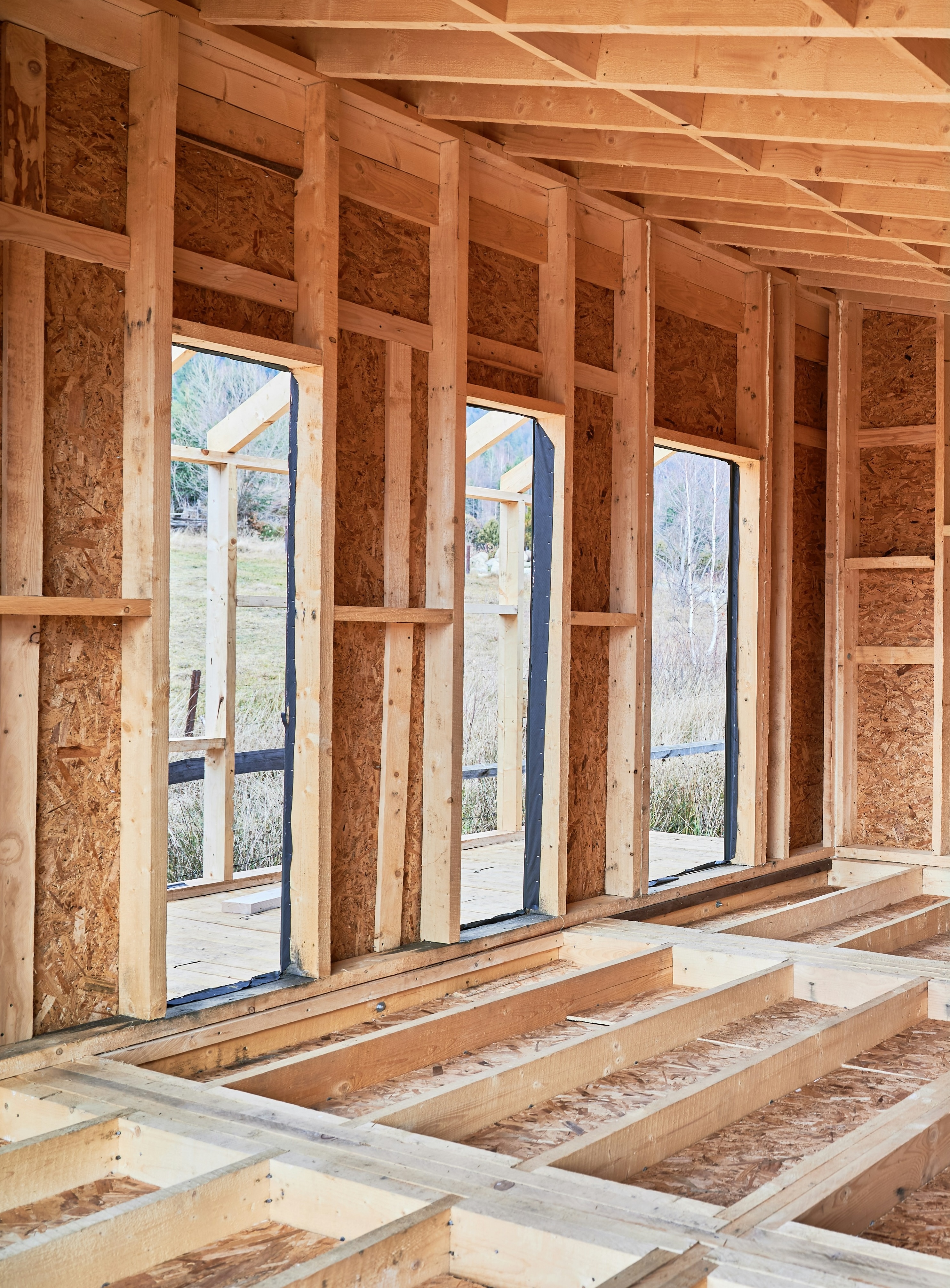 Timber-framed building under construction with window openings