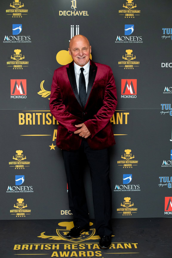 Guest attending the British Restaurant Awards red carpet in front of the branded backdrop